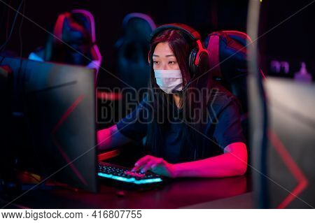 A Young Asian Girl Wearing A Mask Plays Online Video Games In The Evening In A Computer Club