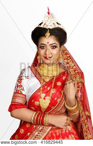 Stunning Indian Bride Dressed In Red Traditional Banarasi Sari Embroidered With Gold Jewellery And A