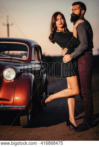 Bearded Brunette Man In A Shirt And Trousers With Suspenders Hugs A Slender Young Girl With Long Hai