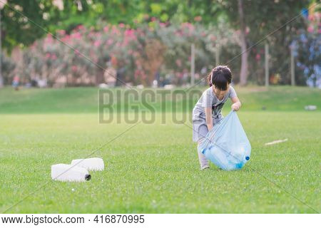 Child Takes Care Of Environment. Cute Asian Girl Keeps Plastic Bottle Bags In Blue Plastic Bag. Chil