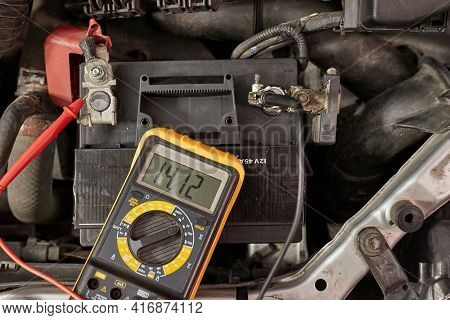 Car starter battery voltage measured with multimeter. Voltage above 14 volts as the alternator is charging the battery. Electric system working well.