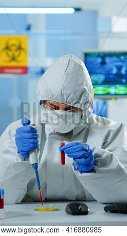 Science Technician In Ppe Suit Using Micropipette And Petri Dish Analysing Blood Sample