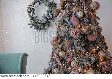 Christmas Tree With Garlands And Decorative Toys. Blue Soft Armchair