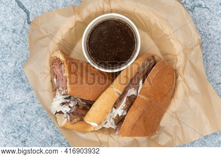 Overhead View Of French Dip Sandwich Is Loaded With Rolled Roasted Beef In Home Made Roll Served Wit