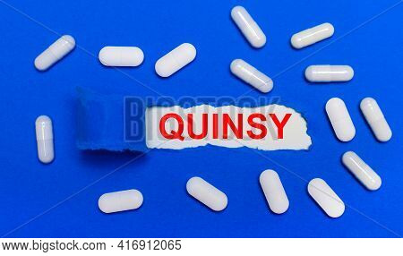 White Pills Lie On A Beautiful Blue Background. In The Center Is White Paper With The Inscription Qu
