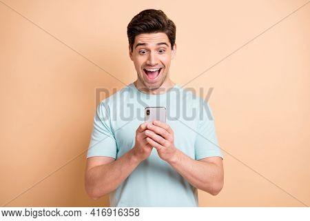 Portrait Of Nice Cheerful Focused Guy Blogger Influenzer Using Device Having Fun Isolated Over Beige