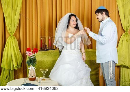 During A Chuppah Ceremony At A Jewish Synagogue Wedding, The Groom Puts A Ring On The Bride's Index 