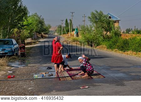Kazarman. Kyrgyzstan. August 12, 2019. The Family Of A Suburban Village Wash Carpets In The Middle O