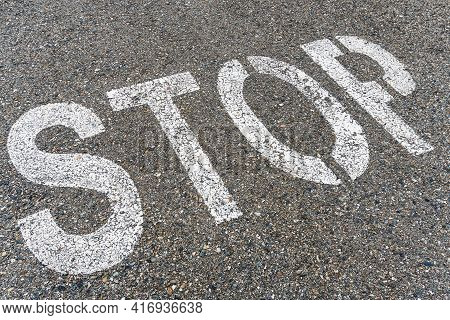 Stop Sign On The Road With Textured Asphalt.