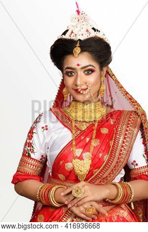 Stunning Indian Bride Dressed In Red Traditional Banarasi Sari Embroidered With Gold Jewellery And A