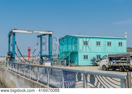 Pyeongtaek, South Korea; April 6, 2021: Green Metal Building Beside Boat Lift With Red Lighthouse In