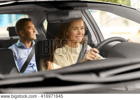 transportation, vehicle and people concept - happy smiling female driver driving car with male passenger