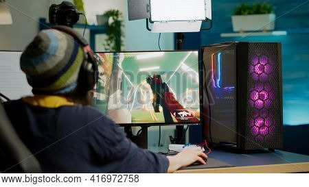 Back Shot Of Pro Streamer With Headphone Playing Fps Videogame