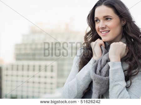 Smiling pretty woman in winter clothes posing outside on a cloudy day