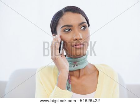 Cheerful elegant woman sitting on sofa in bright living room having a phone call