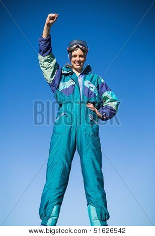 Smiling woman in ski suit putting hand up looking at camera