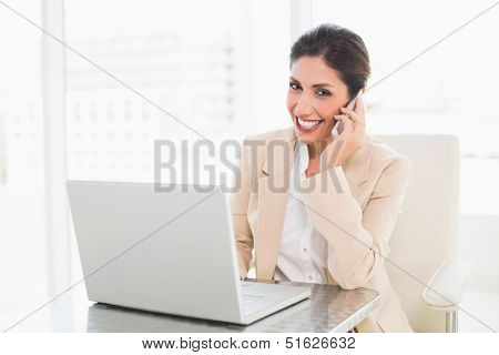 Smiling businesswoman working with a laptop on the phone at the office