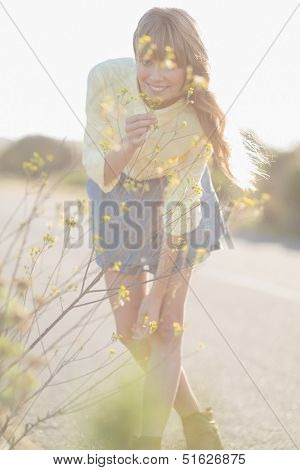 Cheerful hipster girl smelling flowers on a glowing background