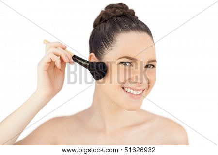 Sensual model using blusher brush while posing on white background