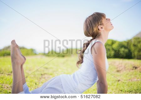 Natural young woman stretching outside in a sunny meadow