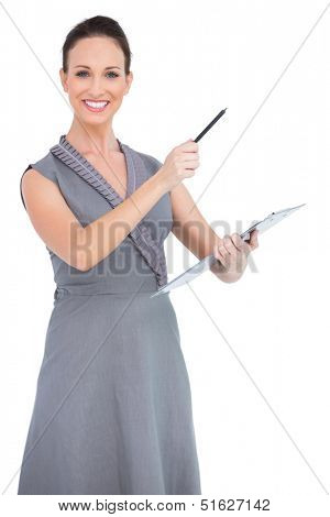 Cheerful seductive model pointing with pen while posing on white background