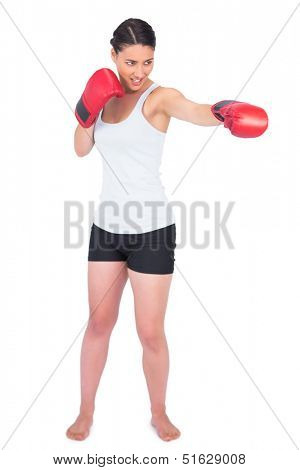 Smiling slender model with boxing gloves punching while posing on white background