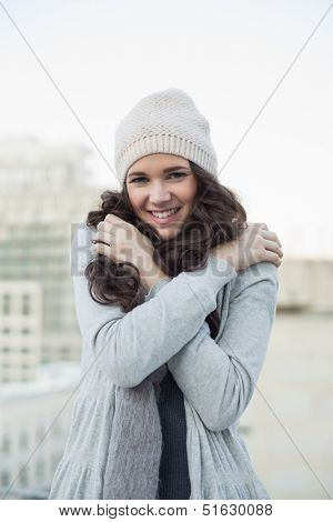 Pretty young brunette shivering outside on a cloudy day