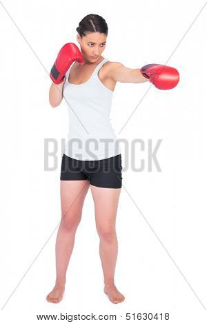 Slender model with boxing gloves punching while posing on white background