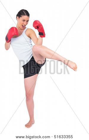 Slender model with boxing gloves kicking while posing on white background
