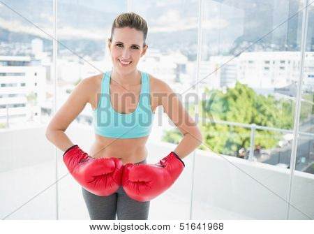 Smiling woman wearing red boxing gloves looking at camera