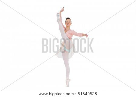 Smiling gorgeous ballerina rising her leg on white background 