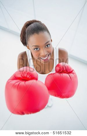 High angle view of cheerful fit woman with red boxing gloves in bright fitness studio