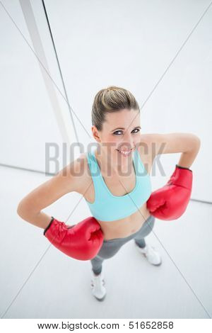 Smiling woman with red boxing gloves posing looking at camera