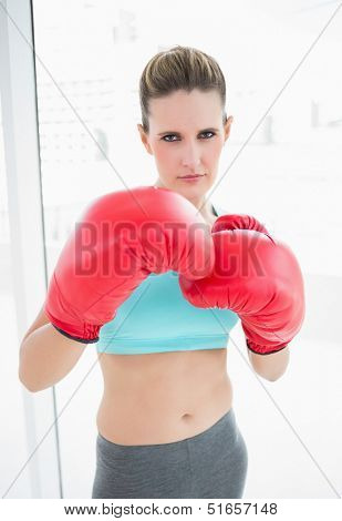 Serious woman wearing red boxing gloves looking at camera