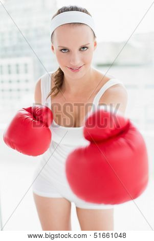 Relaxed pretty sportswoman boxing the camera in a bright room