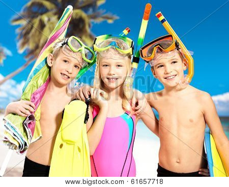 Portrait of the happy children enjoying at beach.  Schoolchild kids standing together in bright color swimwear with swimming mask on head .