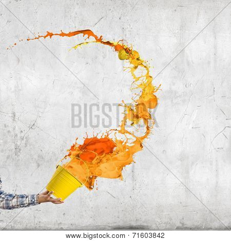 Close up of hand splashing colorful paint from bucket