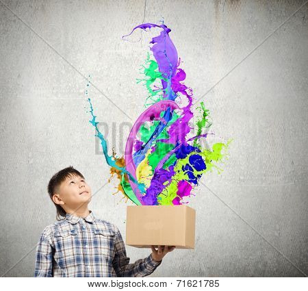Young boy splashing colorful paint from carton box