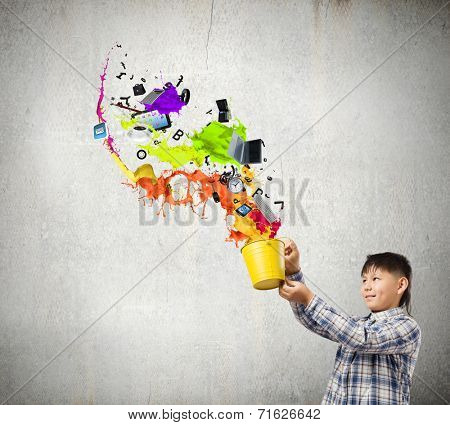 Young boy splashing colorful paint from bucket