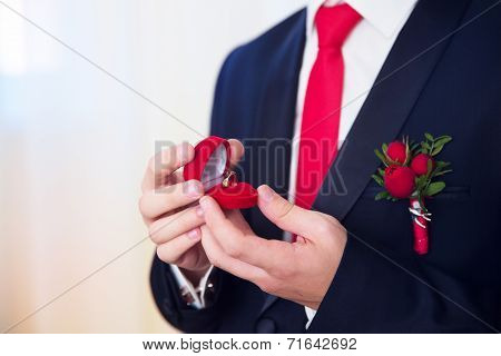 Hands Of Wedding Groom Getting Ready In Suit. The Groom Holds The Box With The Wedding Rings.