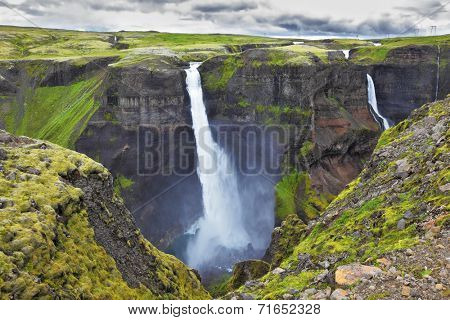 Hayfoss dangerous waterfall in Iceland. Vertical cliff, from which the powerful waterfall flies on black stones