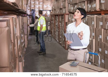 Pretty warehouse manager checking inventory in a large warehouse