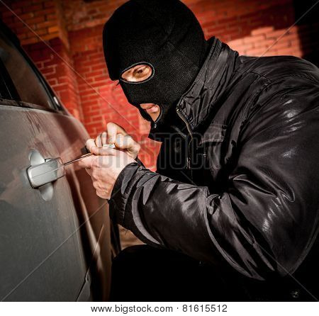 Robber and the car thief in a mask opens the door of the car and hijacks the car.
