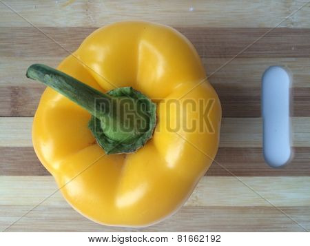 Yellow Pepper With A Green Tail On A Cutting Board