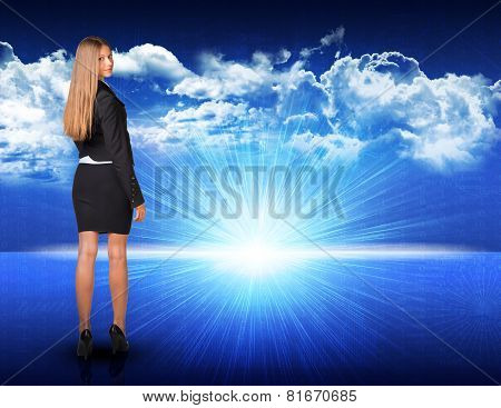Businesswoman standing against blue landscape with rising sun