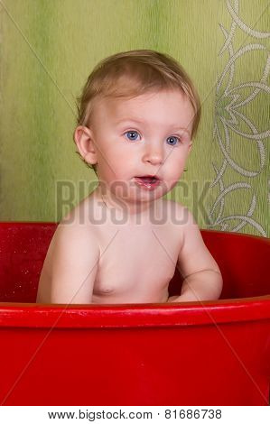 Beautiful little blond girl sitting in the bathroom and chew toys
