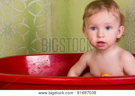 Beautiful little blond girl sitting in the bathroom and chew toys