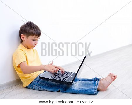 Petit garçon avec ordinateur portable dans une salle vide