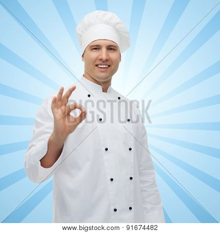 cooking, profession, gesture and people concept - happy male chef cook showing ok sign over blue burst rays background