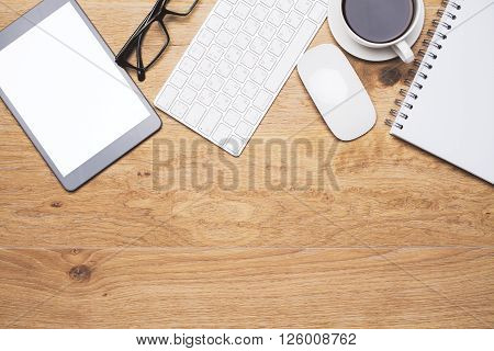Topview of wooden desk with blank tablet keyboard computer mouse and other items. Mock up